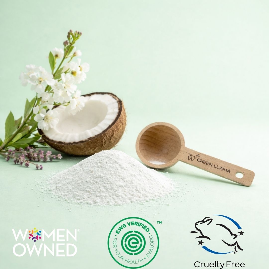 A pile of white powder sits on a pale mint background with a cut coconut, white flowers, and a wooden scoop engraved with the Green Llama brand. Logos for Women Owned, BSG Verified, and Cruelty Free appear at the bottom.
