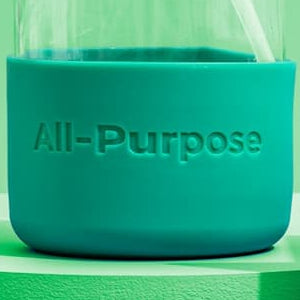 Green Llama all-purpose cleaner bottle with packaging and flowers on a green background