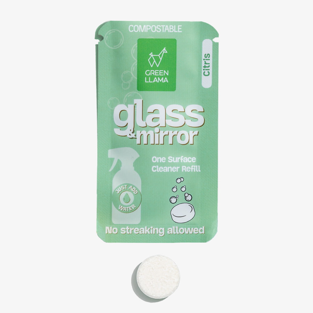 The Green Llama Streak-Free Glass & Mirror Cleaner Kit with Litsea Cubeba Fragrance features a refillable green glass bottle labeled “One Surface Cleaner Refill” and a white cleaning tablet for eco-friendly, streak-free cleaning.