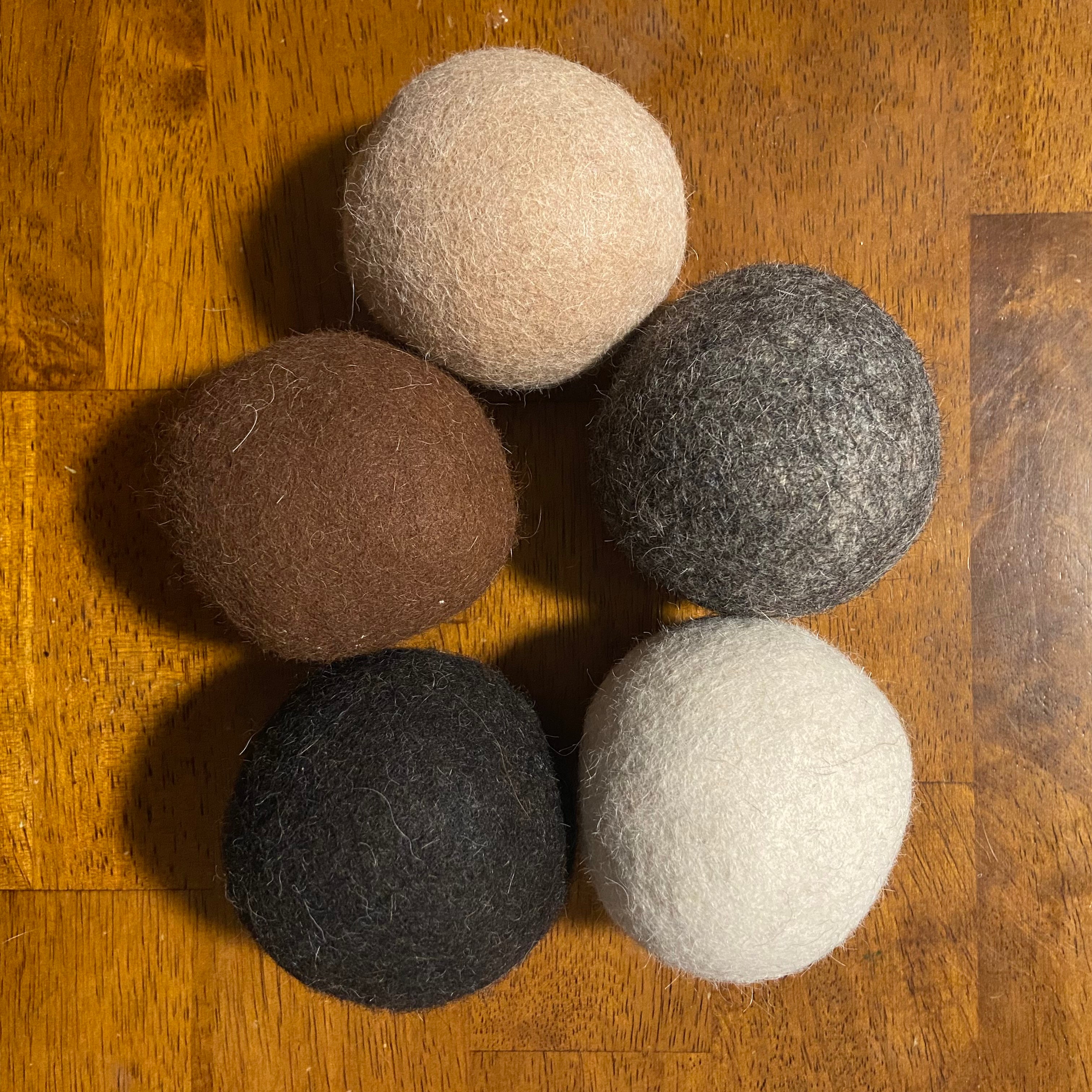 Green Llama’s Locally Sourced Alpaca Dryer Balls (Pack of 3) are arranged on a wooden surface—ideal for eco-friendly laundry and naturally hypoallergenic care.