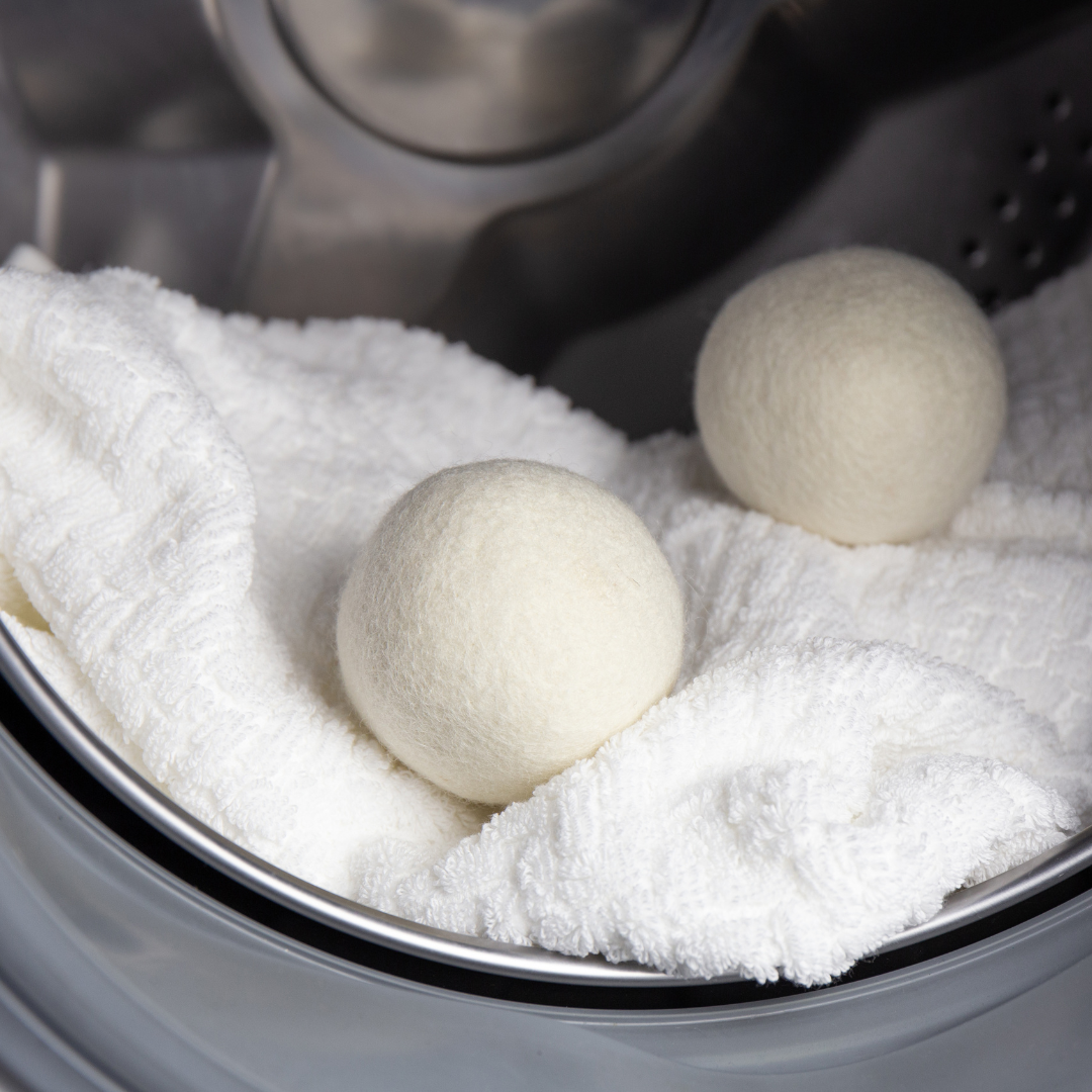 Three Locally Sourced Alpaca Dryer Balls by Green Llama sit on a towel in a washer or dryer, providing a sustainable and hypoallergenic laundry solution.