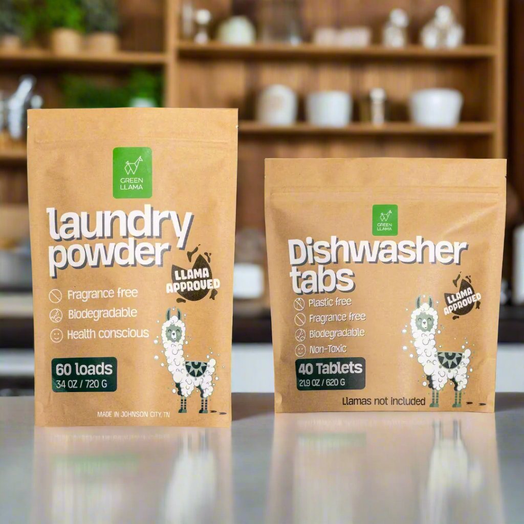 Two brown eco-friendly packages from Green Llama on a kitchen counter: one labeled PVA-free laundry detergent, the other dishwasher tabs. The Ultimate Non-Toxic Home Bulk Bundle offers plant-powered, biodegradable, non-toxic cleaning with fun llama cartoons.
