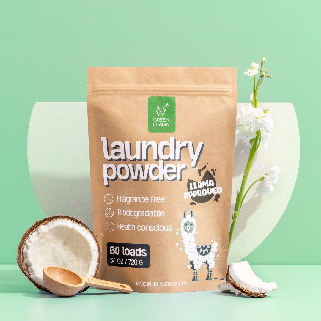 A Green Llama Digital Gift Card is displayed upright, surrounded by coconut halves, a wooden spoon, and white flowers—highlighting eco-friendly gifting for sustainable living—all set against a pastel green background.